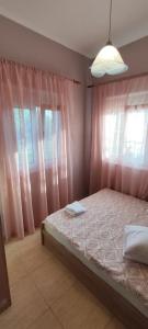 a bedroom with pink curtains and a bed with two towels at Heaven House in Sozopoli