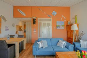 - un salon avec un canapé bleu et un mur orange dans l'établissement Appartement Celina - Residence Juliana Julianadorp aan Zee, à Julianadorp