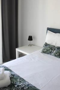 Una cama con sábanas blancas y una mesa con lámpara. en StuDio 57 (5), en Néa Khilí