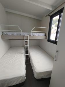 2 stapelbedden in een kleine kamer met een raam bij Bungalow Duemo Camperpark in Águilas