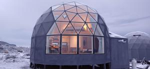 una pequeña casa negra con grandes ventanas de cristal en Dome with Stunning Glacier & Mountain Views en Puerto Natales
