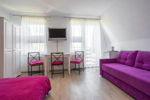 uma sala de estar com um sofá roxo e cadeiras em Pokoje u Kasi em Mielno