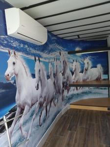 a mural of white horses running on a wall at Leonchic - Guest House com Piscina de Água Salgada in Barcelos