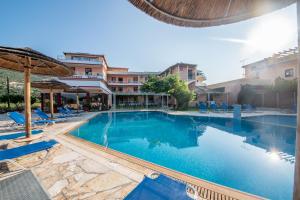 a large swimming pool with blue chairs and a building at Kalias Hotel in Vasiliki