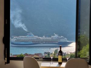 um grande navio de cruzeiro no oceano através de uma janela em DM Apartments em Kotor