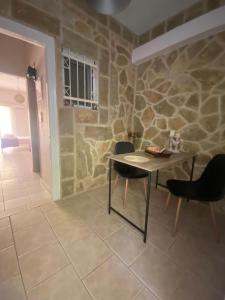 stół i krzesła w pokoju z kamienną ścianą w obiekcie Seaside pearl w mieście Ligia