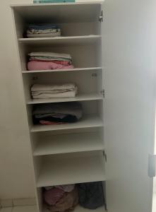 a closet with white shelves and folded clothes at Localizada no centro de Juazeiro in Juazeiro
