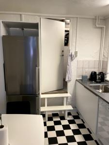 a small kitchen with a refrigerator and a checkered floor at Udbyhøjvejens overnatning in Randers