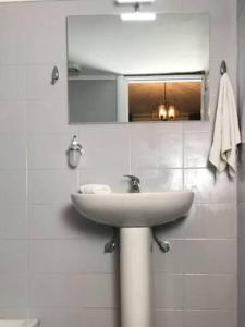 een witte badkamer met een wastafel en een spiegel bij StuDio 57(10) in Néa Khilí