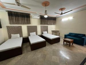 una camera con due letti e un divano blu di Decent Lodge Guest House F-11 a Islamabad