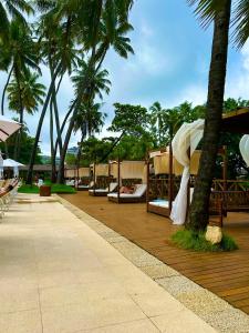 un complejo con camas y palmeras en una terraza en Jatiuca Suítes Resort FLAT en Maceió