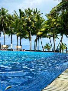 uma piscina com palmeiras na praia em Jatiuca Suítes Resort FLAT em Maceió