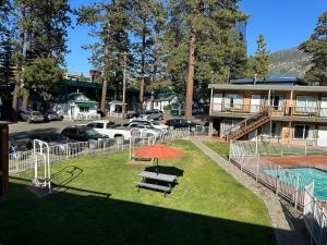 uma mesa de piquenique com um guarda-sol ao lado de uma piscina em Alpine Inn & Spa em South Lake Tahoe