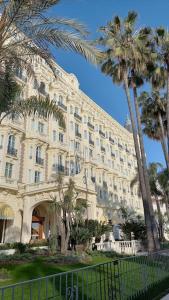 un grande edificio con palme di fronte di Cannes Isola Bella entre mer et montagne a Cannes