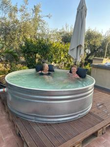 two people in a hot tub with an umbrella at la Tana di Luna in Adrano