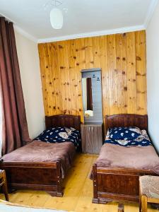 two beds in a room with wooden walls and wooden floors at Manoni Ratiani's Hostel in Soli