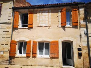 stary budynek z drewnianymi drzwiami i oknami w obiekcie Maison de ville près du port w mieście Bourg-sur-Gironde