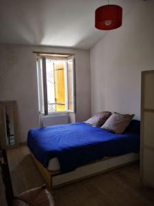 sypialnia z niebieskim łóżkiem i oknem w obiekcie Maison de ville près du port w mieście Bourg-sur-Gironde