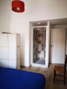 sypialnia z niebieskim łóżkiem i drzwiami do prysznica w obiekcie Maison de ville près du port w mieście Bourg-sur-Gironde