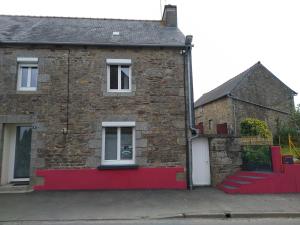 una casa de ladrillo con porche delantero rojo en Gîte familial, en Plouguenast Langast