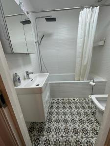 a bathroom with a sink and a tub and a toilet at Cosy Studio Flat at Gants Hill Station, Ilford, Essex, London in Wanstead