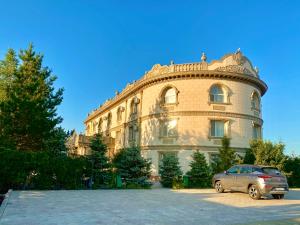 a car parked in front of a large building at Hotel Astam in Kostanay