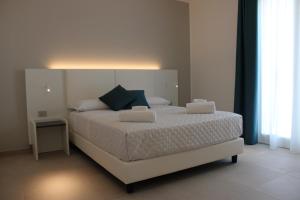 a bedroom with a large white bed with blue pillows at Coral Sand bed and breakfast in San Vito lo Capo