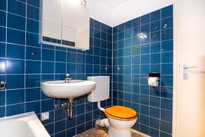 Baño de azulejos azules con aseo y lavamanos en Hansa Apartment mit Schwimmbad, direkt am Hansapark, en Sierksdorf