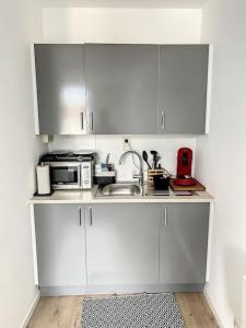 a kitchen with white cabinets and a sink and a microwave at Station 173 D Bruxelles-charleroi-airport in Charleroi