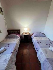 a room with two beds and a table with a lamp at La casa del Rio en Sauce Viejo - Santa Fe- in Sauce Viejo