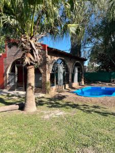 una casa con una palmera y una piscina en La casa del Rio en Sauce Viejo - Santa Fe- en Sauce Viejo