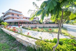 a palm tree and flowers in front of a building at Kalias Hotel in Vasiliki