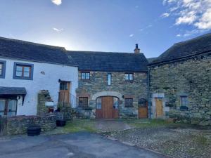an old stone house with wooden doors and a yard at Swallows Barn in Penrith