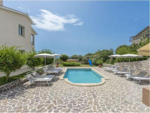 a swimming pool with chairs and umbrellas next to a building at Villa Tomko in Brovinje