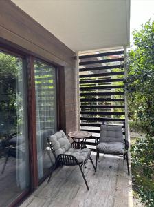 a patio with two chairs and a table on a porch at Dreamland Oasis 1st floor Apartment With a Garden by the Sea in Chakvi +40 photos