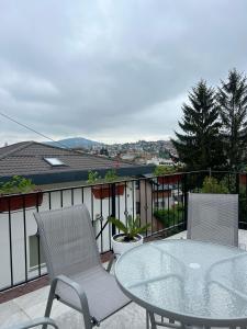 eine Terrasse mit einem Glastisch und Stühlen auf dem Balkon in der Unterkunft Apartment 528 in Sarajevo