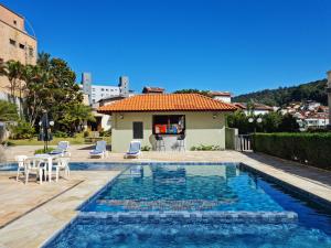 een zwembad met stoelen en een tafel en een huis bij Hotel CasaBlanca in Águas de Lindóia