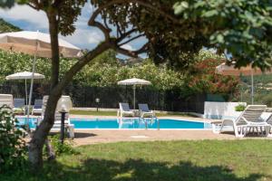 a swimming pool with chairs and umbrellas and a pool at Hotel Biderrosa in Cala Liberotto