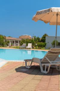 a chair and an umbrella next to a swimming pool at Hotel Biderrosa in Cala Liberotto