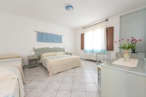 a bedroom with a bed and a table with flowers at Hotel Biderrosa in Cala Liberotto