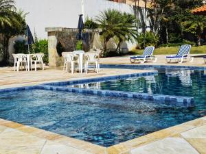 a swimming pool with chairs and a table and chairs at Hotel CasaBlanca in Águas de Lindoia