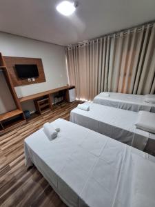 a hotel room with two beds and a flat screen tv at Hotel Reserva do Xingó in Piranhas