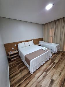 a bedroom with two beds and a wooden floor at Hotel Reserva do Xingó in Piranhas