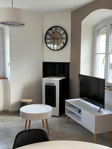 sala de estar con TV y reloj en la pared en L'escale des roses en Doué-la-Fontaine