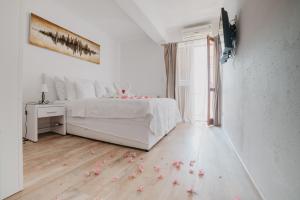 a white bedroom with a white bed and flowers on the floor at Black Pearl Tisno in Tisno