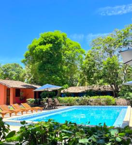 a pool with chairs and umbrellas next to a building at Pousada Canto do sabiá Imbassaí in Imbassai