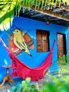una pintura de un pájaro amarillo colgado en una cuerda roja en Pousada Canto do sabiá Imbassaí, en Imbassai
