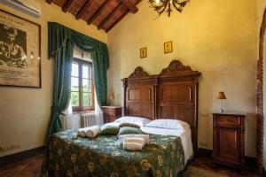 Schlafzimmer mit einem großen Bett mit einem Kopfteil aus Holz in der Unterkunft Casale Baldelli Apartments in Castiglione del Lago