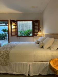 a bedroom with a large white bed with a window at Taiba Desert Point in Taíba