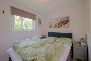 a bedroom with a bed and a window at Chalet Riviéra - Camping De Watersnip Sint Maartenszee in Petten